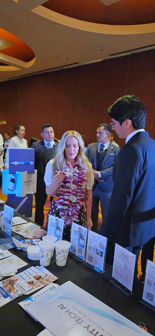 Ninfa Salinas observa los materiales informativos de Longevity Clinic sobre la mesa del stand en el evento Somos Grandes, Galería Plaza Veracruz
